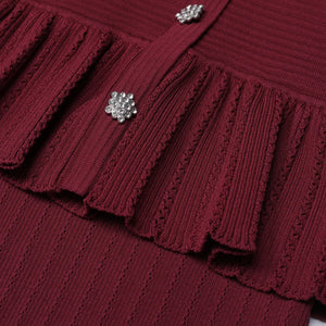 Close-up of a burgundy knitted garment with decorative buttons.