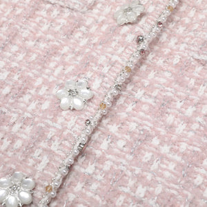 Close-up of a decorative headband with flowers and beads on a textured pink background