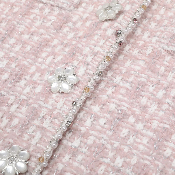 Close-up of a decorative headband with flowers and beads on a textured pink background