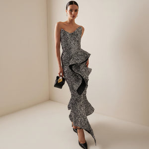 Woman wearing a black and white patterned dress with ruffled details on a neutral background