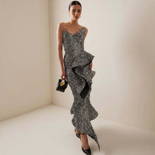 Woman wearing a black and white patterned dress with ruffled details on a neutral background