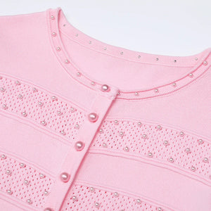 Close-up of a pink garment with pearl embellishments on a light gray background