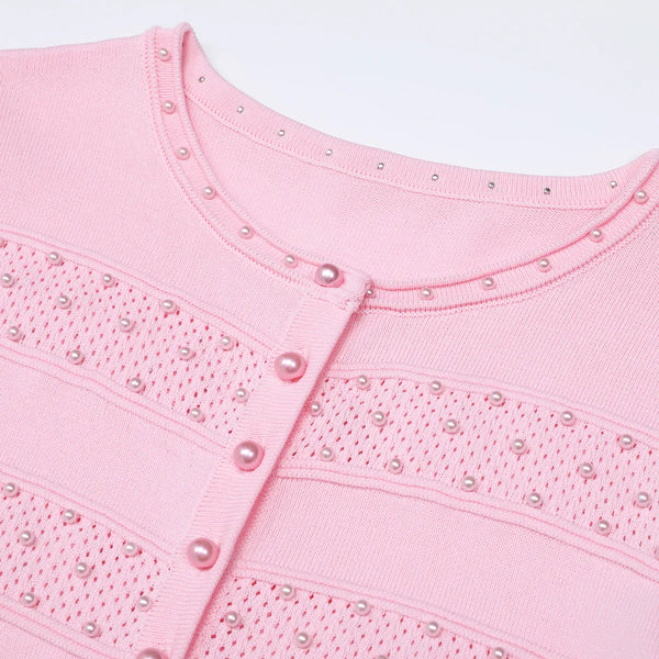 Close-up of a pink garment with pearl embellishments on a light gray background
