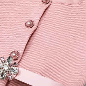 Close-up of a pink garment with decorative buttons and a bow.