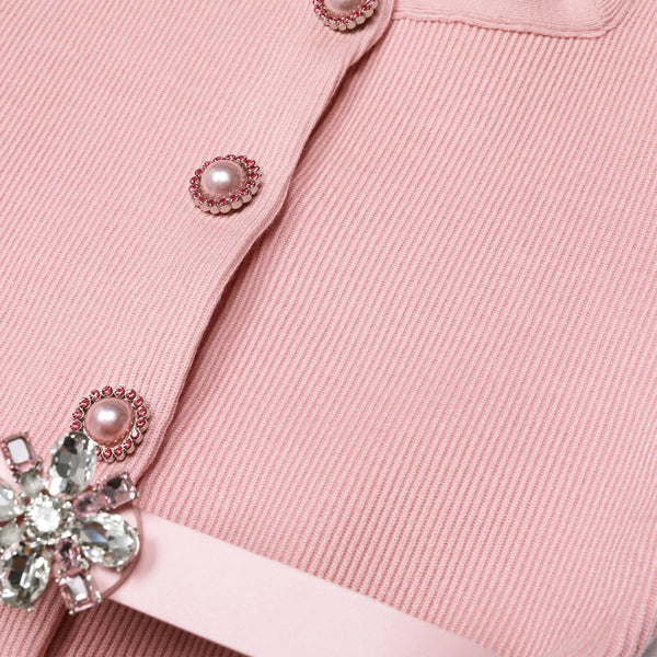 Close-up of a pink garment with decorative buttons and a bow.