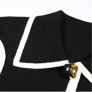 Black blazer with white trim and gold buttons on a white background