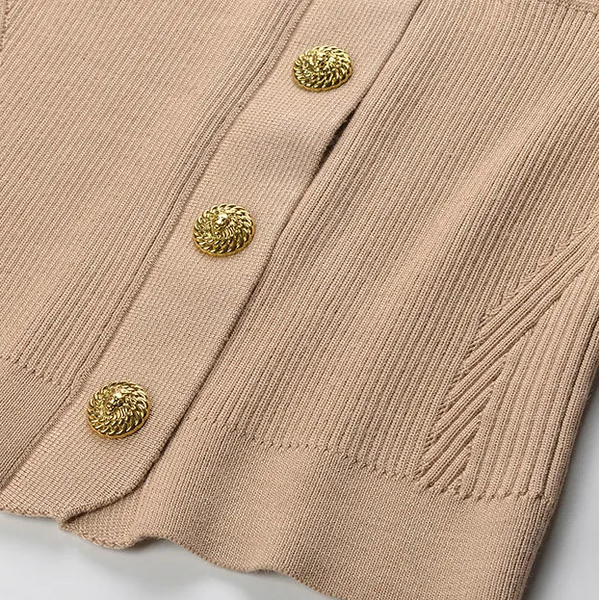 Close-up of a beige ribbed sweater with gold buttons on a light gray background