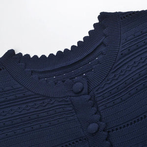 Close-up of a navy blue textured sweater with button details on a white background