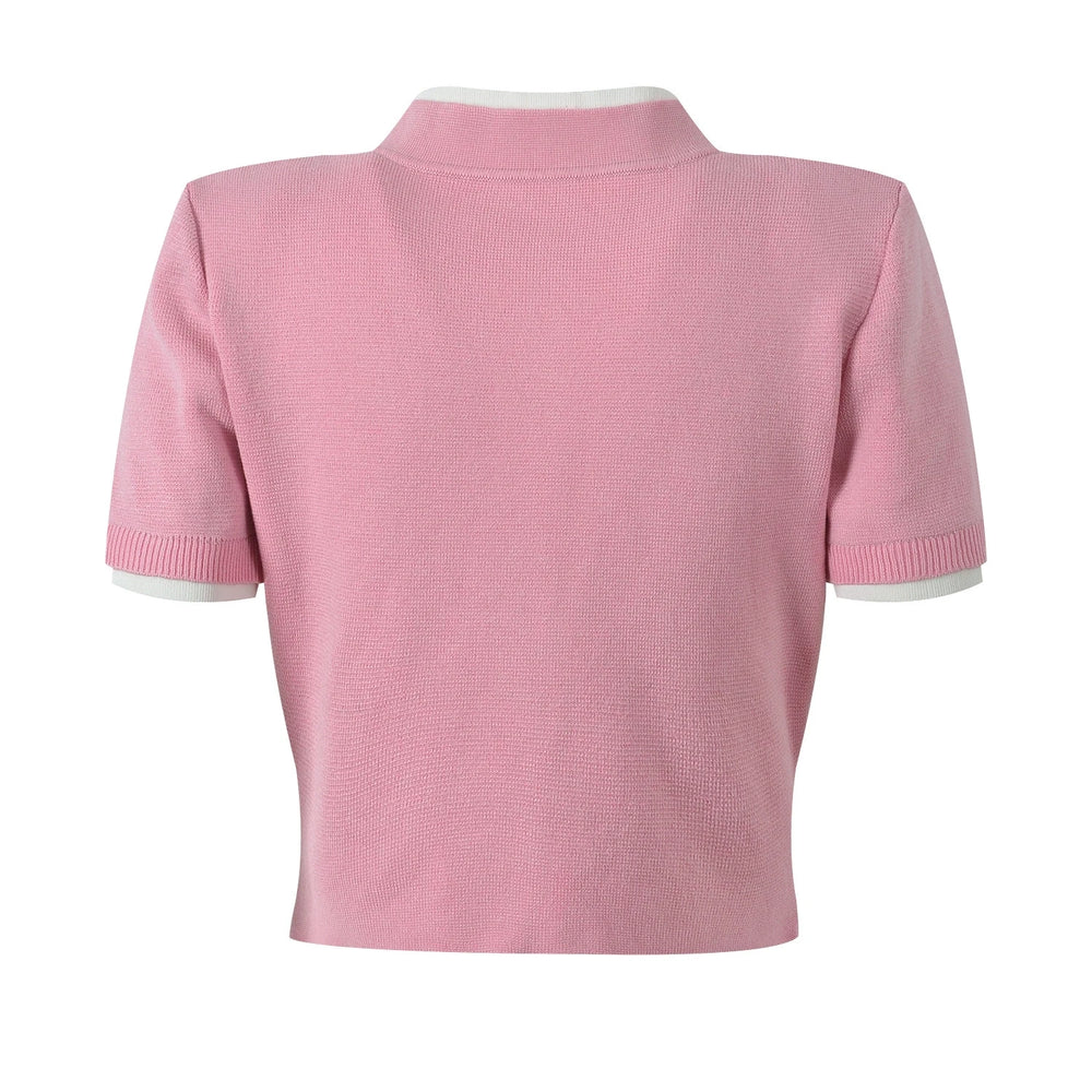 Pink cardigan with white buttons and a decorative flower on a white background