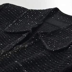 Close-up of a black textured garment with a collar on a white background