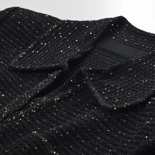 Close-up of a black textured garment with a collar on a white background