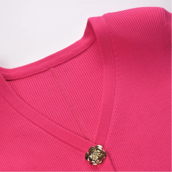 Close-up of a pink garment with a gold button on a white background
