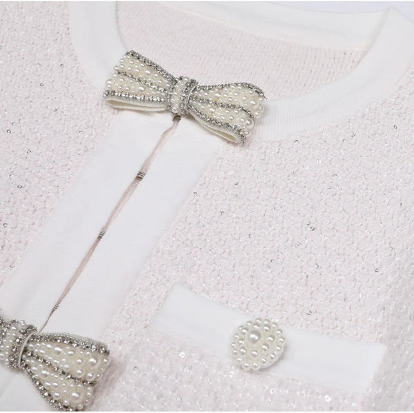 Close-up of a textured white fabric with decorative bow pins on a light gray background