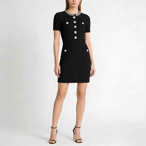 Black dress with white buttons worn by a model on a white background
