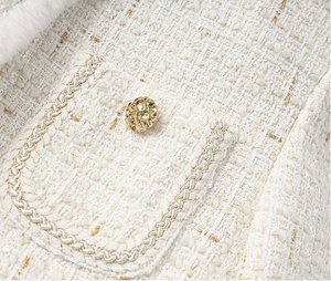 Close-up of a textured white fabric with a gold chain and decorative element.