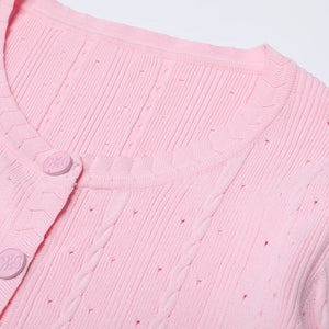 Close-up of a pink textured garment with buttons on a light gray background