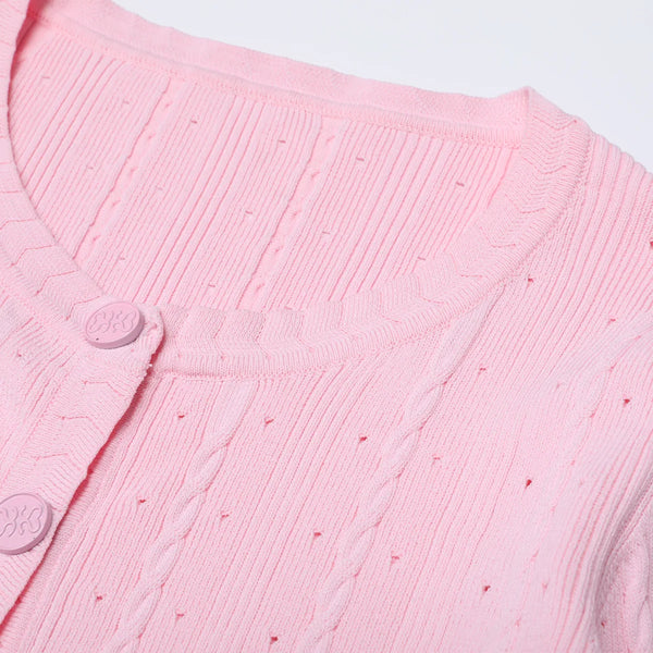 Close-up of a pink textured garment with buttons on a light gray background