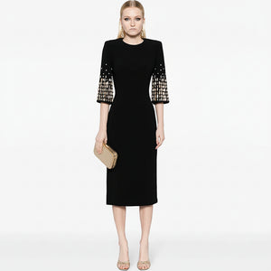 Black dress with patterned sleeves worn by a model on a white background