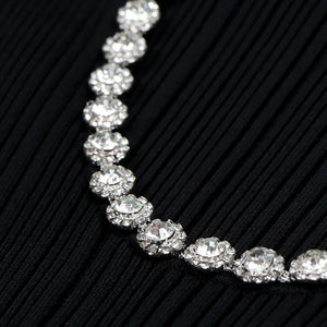 Silver necklace with clear stones on a black textured background