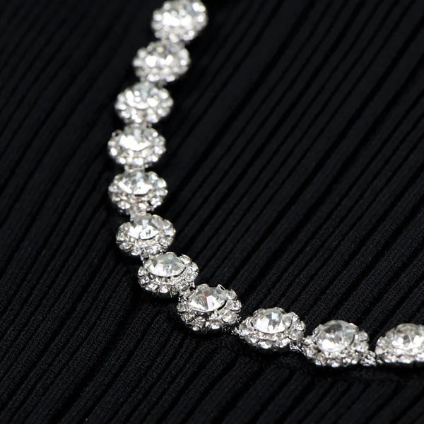 Silver necklace with clear stones on a black textured background