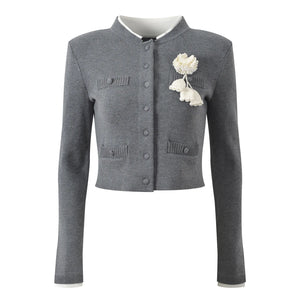 Gray cardigan with white floral brooch on a white background