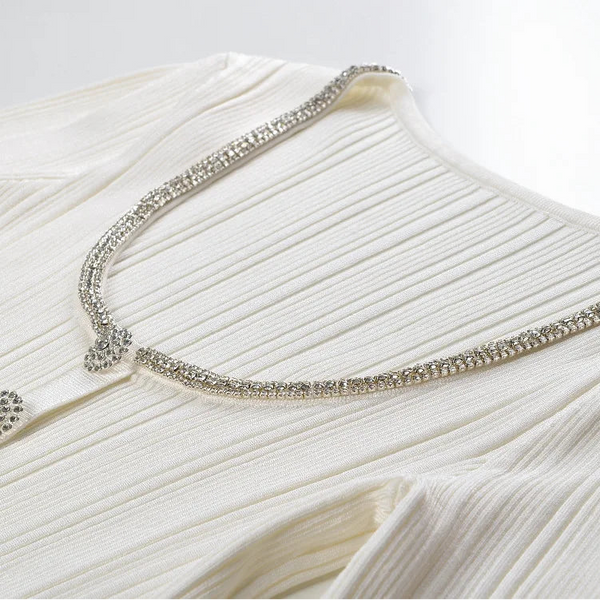 Close-up of a white dress with a decorative silver trim on a light background