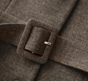 Close-up of a brown belt with a buckle on a textured fabric background