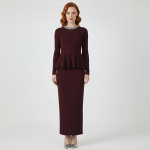 Woman wearing a burgundy peplum top and skirt set on a white background