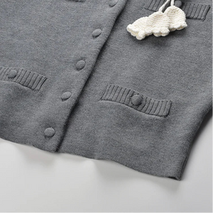 Gray cardigan with cloud-shaped decorative item on a light background