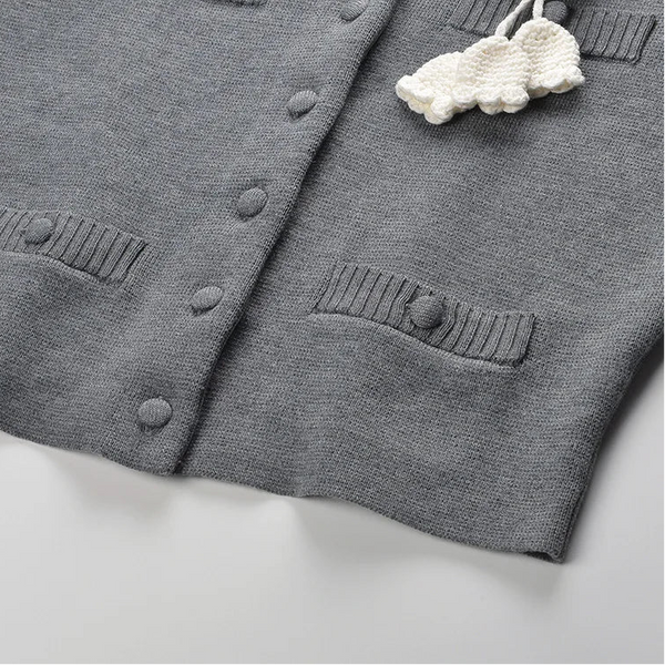 Gray cardigan with cloud-shaped decorative item on a light background