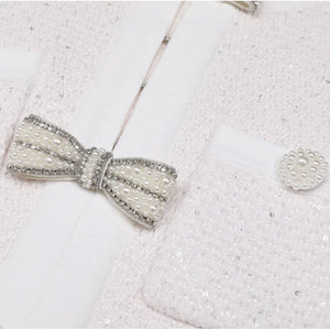 Silver bow tie and cufflinks on a textured white surface