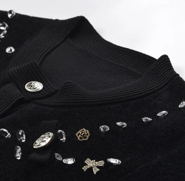 Black sweater with decorative buttons and embellishments on a white background