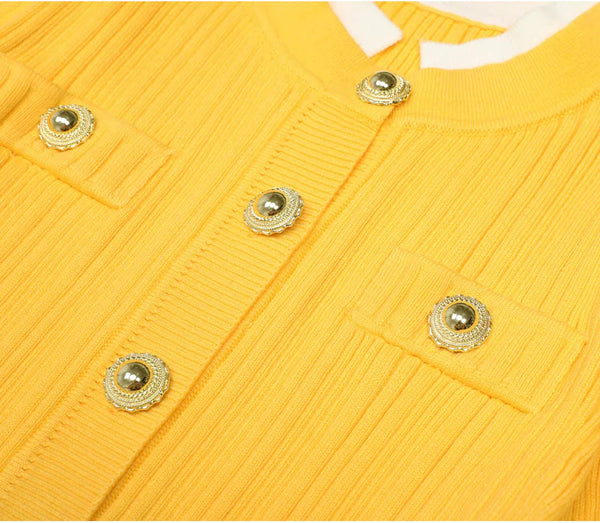 Close-up of a yellow textured garment with gold buttons on a white background