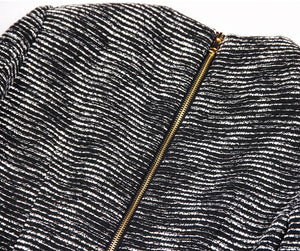 Close-up of a textured black and white fabric with a gold zipper.