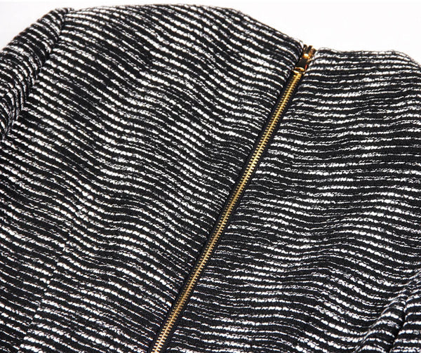 Close-up of a textured black and white fabric with a gold zipper.