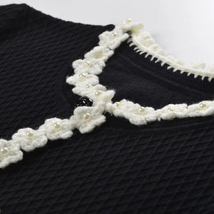 Black sweater with white floral lace collar on a white background
