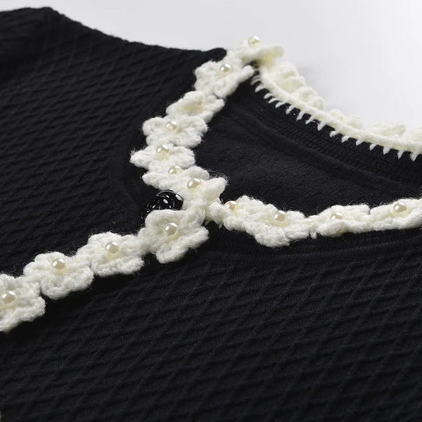 Black sweater with white floral lace collar on a white background