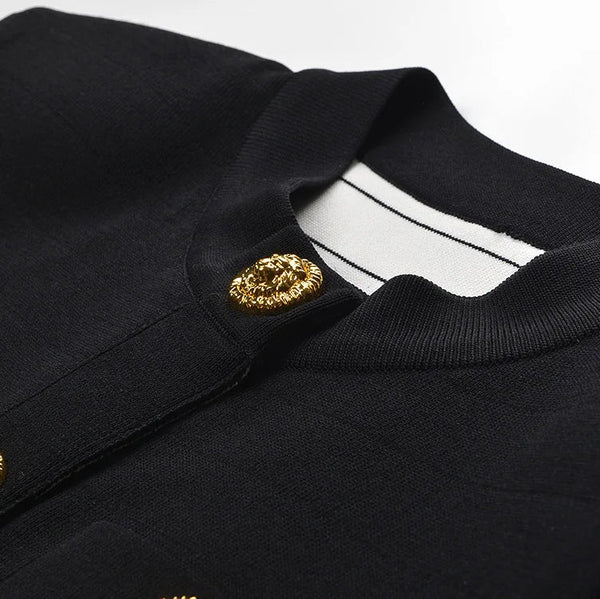 Close-up of a black garment with gold buttons and emblem on a white background