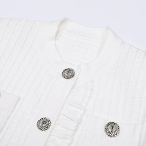 Close-up of a white textured garment with decorative buttons on a light gray background