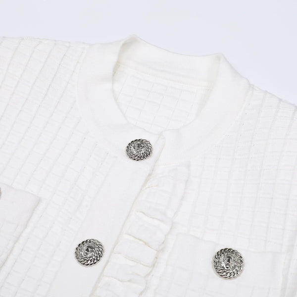 Close-up of a white textured garment with decorative buttons on a light gray background
