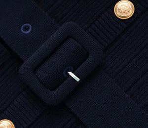 Close-up of a navy blue textured fabric with gold buttons and a buckle.