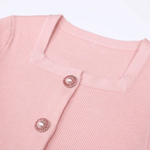 Close-up of a pink textured garment with decorative buttons on a light pink background