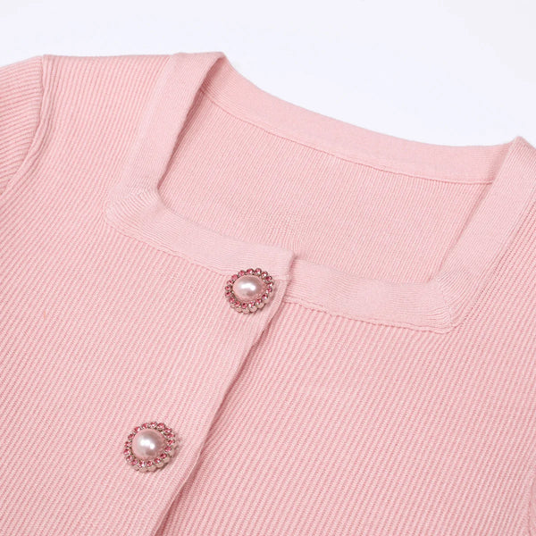 Close-up of a pink textured garment with decorative buttons on a light pink background