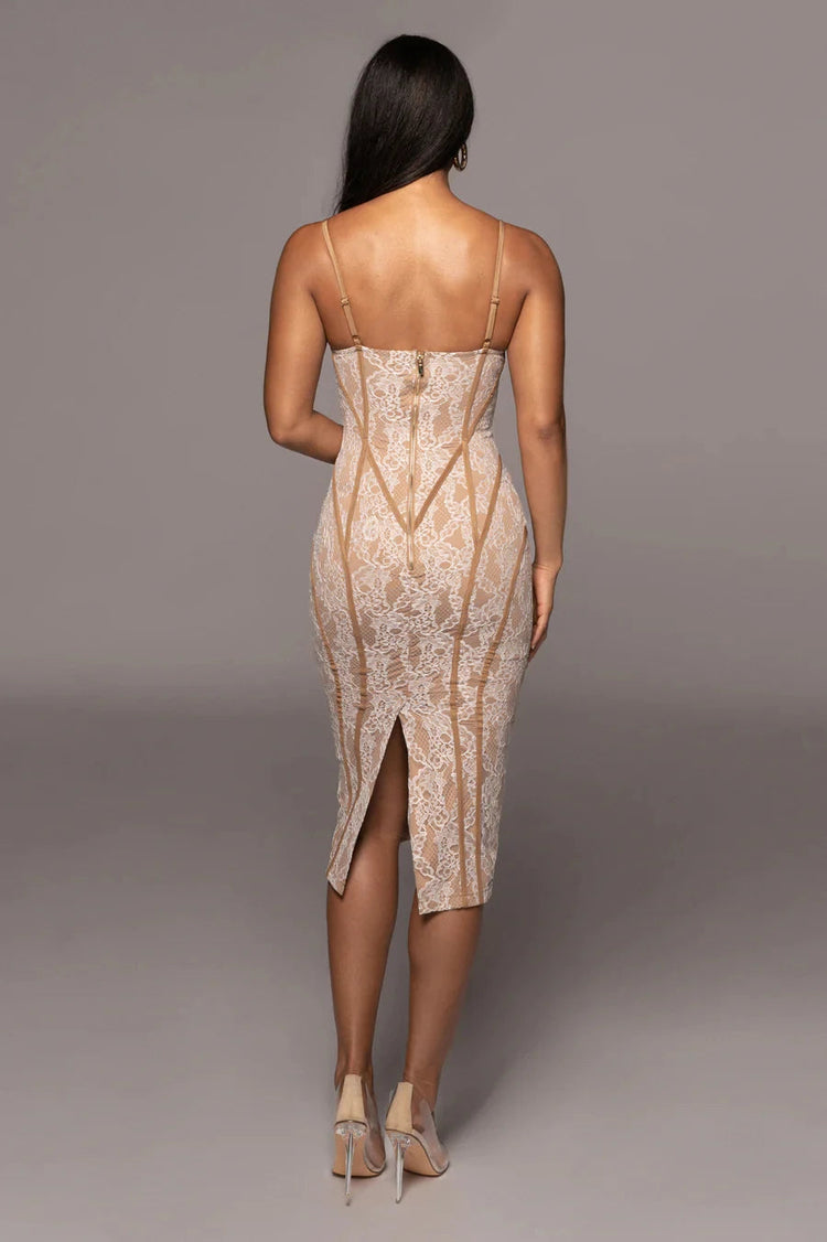 Woman wearing a beige dress with a subtle pattern on a gray background