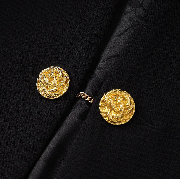 Gold earrings on a black fabric background
