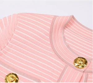 Close-up of a pink textured bag with gold buttons on a light gray background