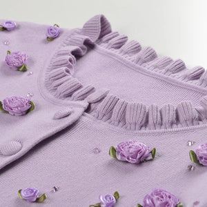Purple sweater with floral embellishments on a white background
