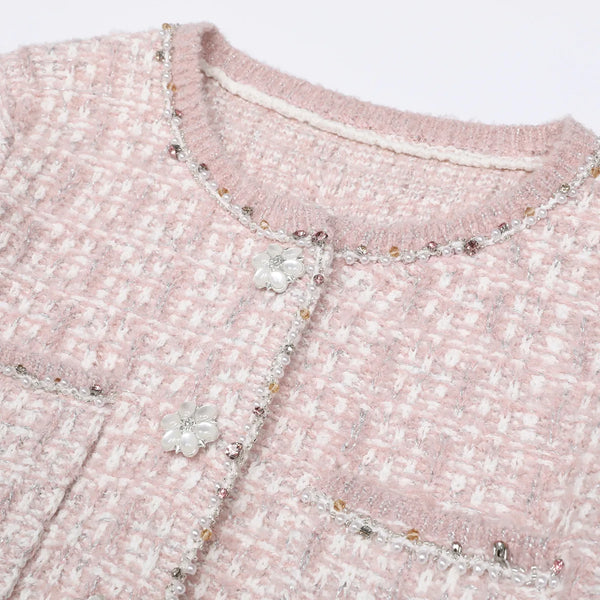 Close-up of a pink textured fabric with floral embellishments and bead details.