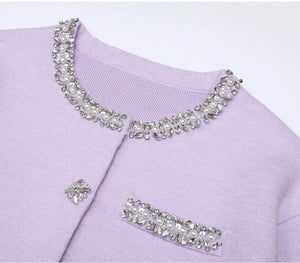 Lavender sweater with decorative crystal embellishments on a white background