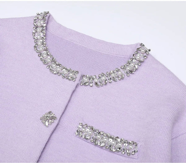 Lavender sweater with decorative crystal embellishments on a white background